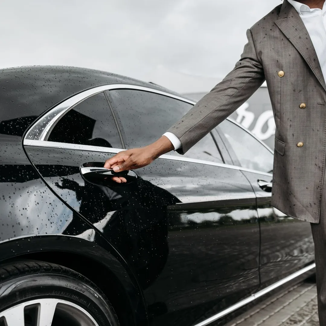 Chauffeur opening door of executive black sedan